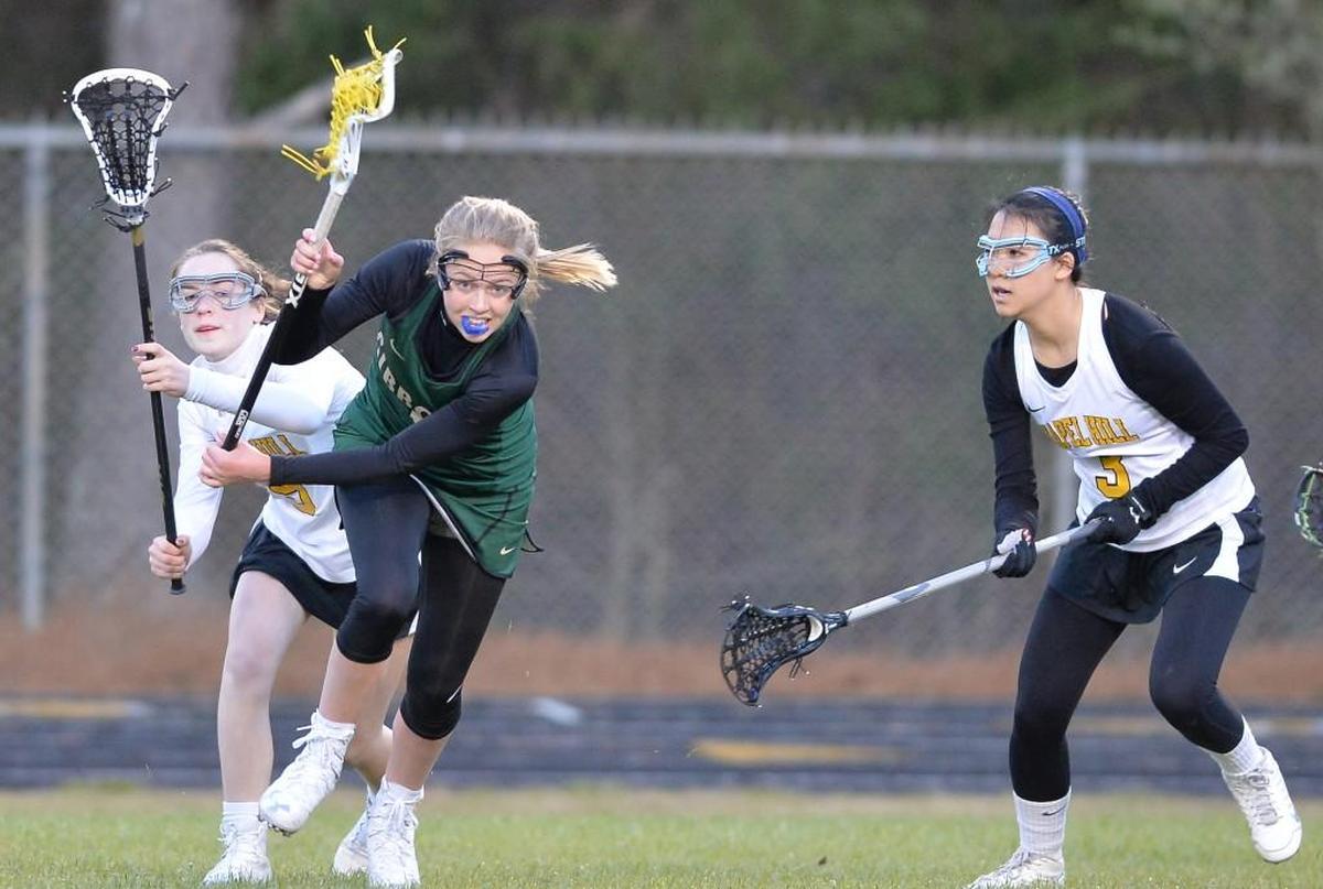 Jordan Lappin, center, of Cardinal Gibbons moves the ball against Anna Blythe, left, and Cassie Xin, right, of Chapel Hill. The Chapel Hill Tigers played the Cardinal Gibbons Crusaders in Chapel Hill, N.C. on Thursday, March 16 2017. Cardinal Gibbons won 18-2.