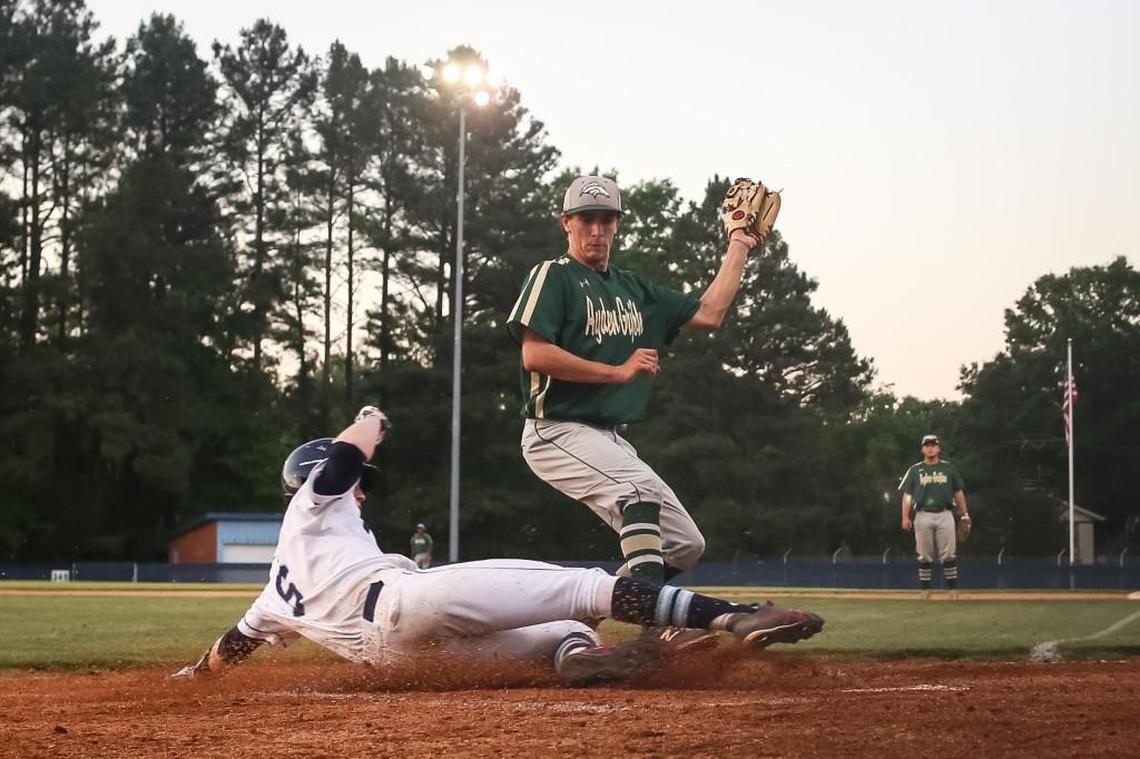 South Granville's Tucker Brown (6) slides into home plate ahead of the tag by Ayden-Grifton pitcher Dakota Delisi (12) during Ayden-Grifton's 2A playoff baseball game at South Granville on Tuesday, May 16, 2017. South Granville won the game 13-2.