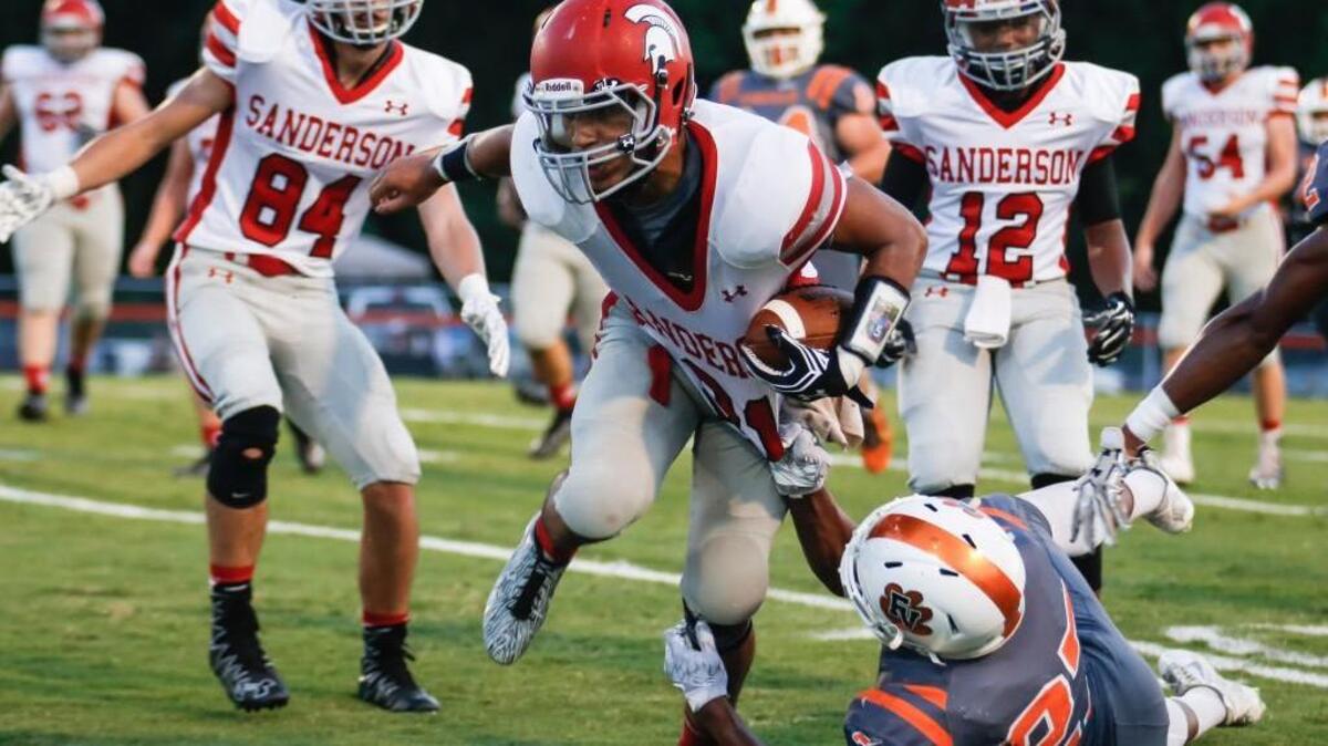 Sanderson running back Jordan Logan (31) runs through the tackle attempt of Fuquay-Varina defender Malcolm Croom (27) during Sanderson's football game at Fuquay-Varina on Friday, August 26, 2016.