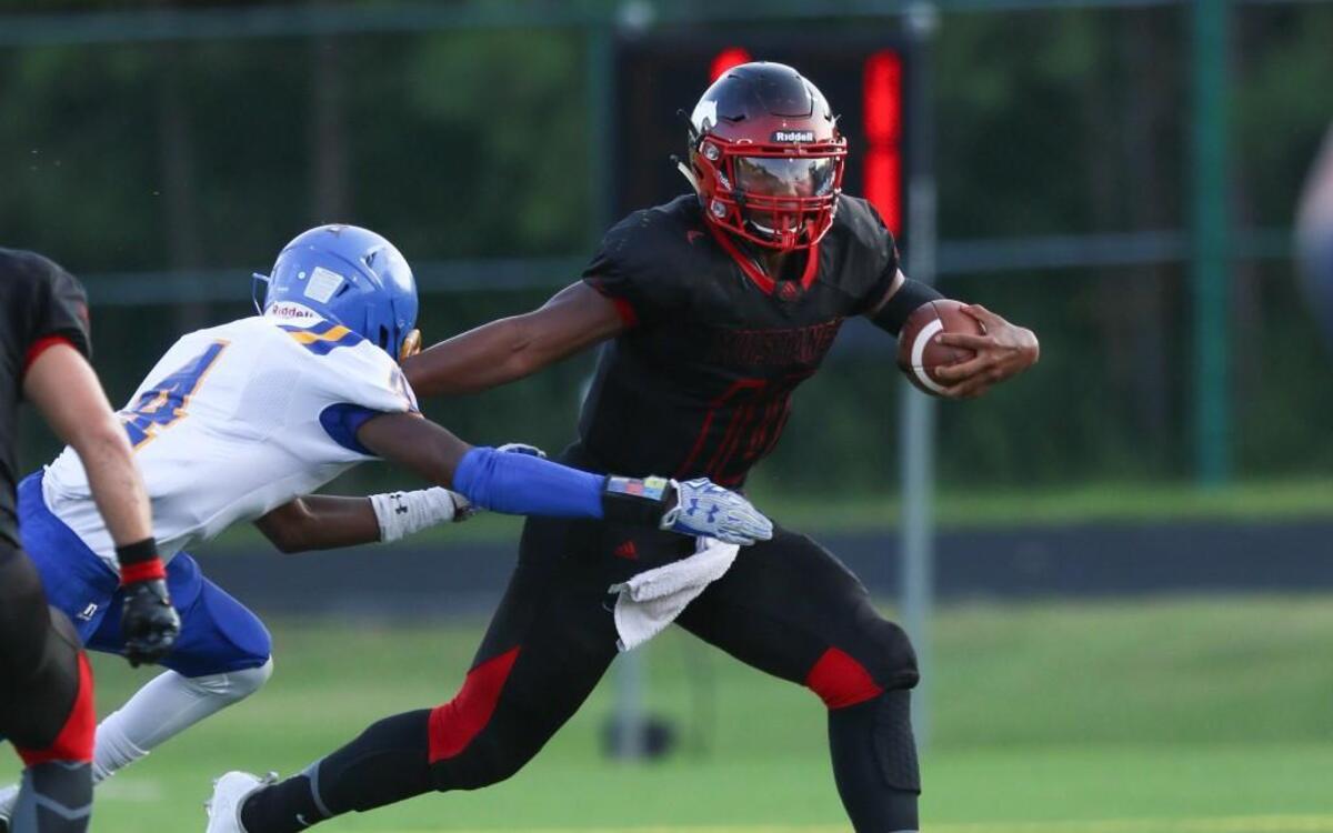 Middle Creek's Domninque Shoffner (12) fends off Garner's Willie Frederick (4) as he picks up yard around end. Coverage from the prep football game between the Garner Trojans and the Middle Creek Mustangs played in Apex, N.C. on Monday, September 5, 2016. Middle Creek defeated Garner 30-10.