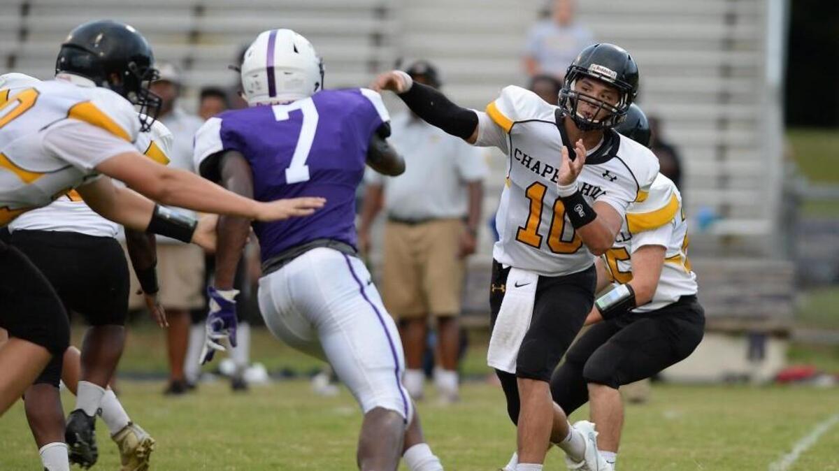 Quarterback Alec Stough (10) of Chapel Hill throws a pass under pressure from Jeffrey Gunter (7) of Riverside. The Riverside Pirates played the Chapel Hill Tigers in a football game that took place in Durham, N.C. on Friday, August 19, 2016.