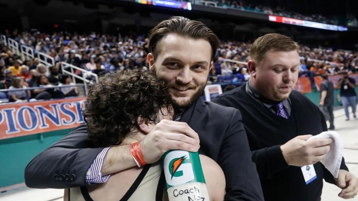 Holly Springs wrestling coach Nick Nosbisch (center) embraces Cam Devers after Devers became the school's first wrestling state champion. Photo from the NCHSAA State Wrestling Championships in Greensboro on Saturday, February 20, 2016.