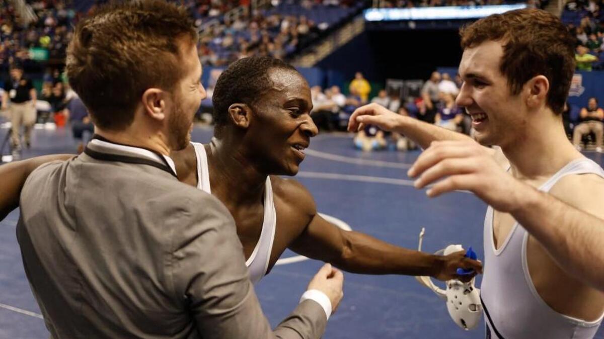 Cary's Kollin Wade, center, celebrates with coach Taylor Cummings and teammate Will Clark after his victory in the 4A 145-lb championship match in the NCHSAA State Championships in Greensboro, NC, on Saturday, February 21, 2015. Wade won the match 3-1 in overtime, and Clark won his second consecutive state championship 13-6 in the 138-lb match.