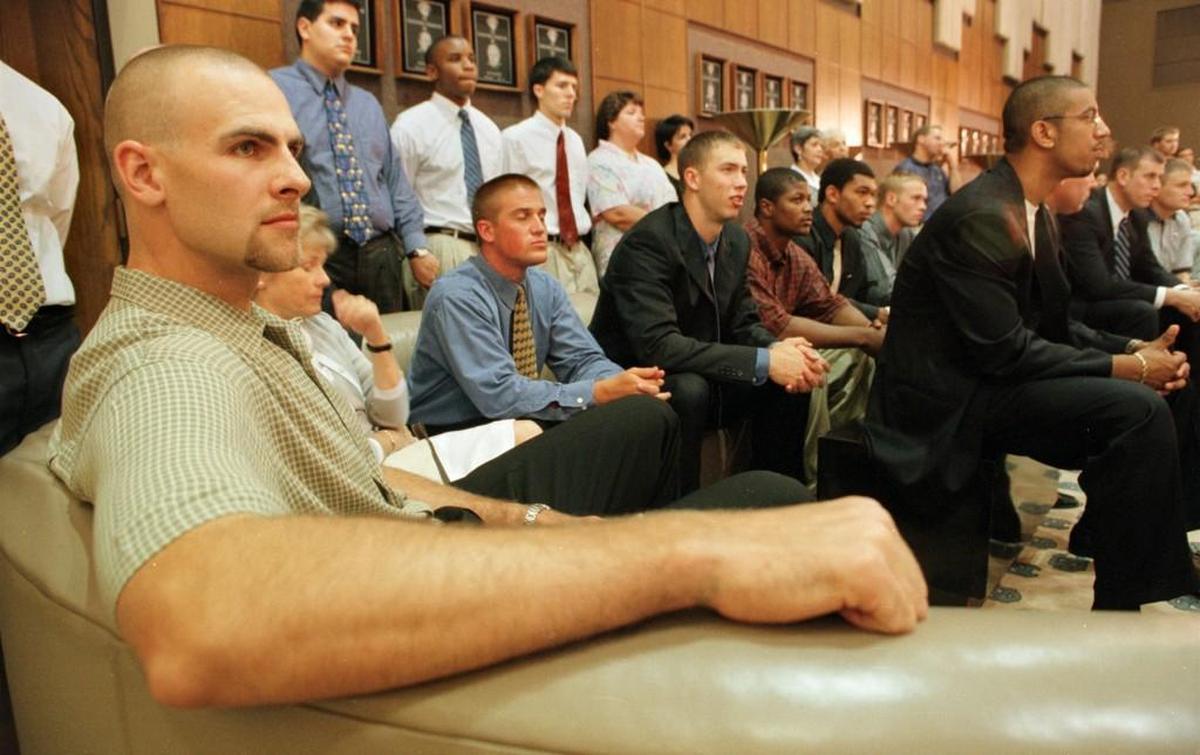 Former North Carolina basketball star Eric Montross left, is surrounded by former and current UNC basketball players as he listens to Tar Heels’ basketball coach Bill Guthridge announces his retirement.