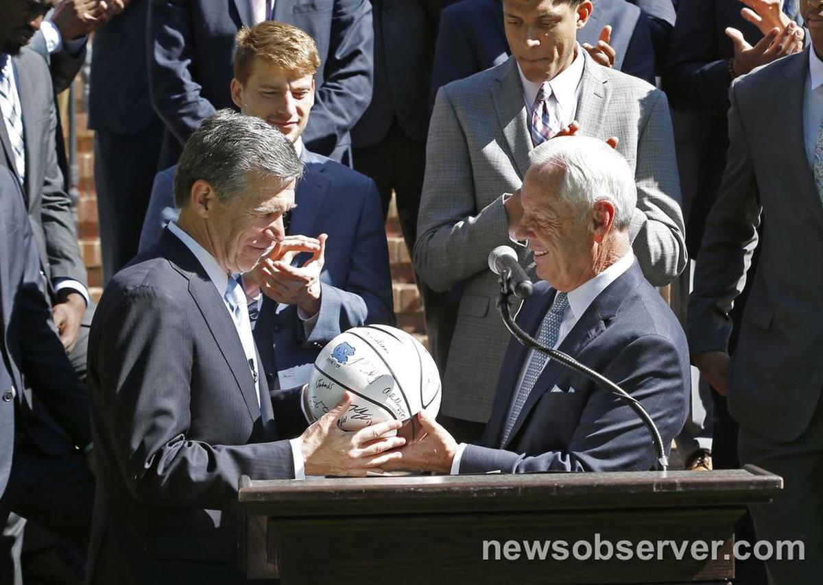 UNC head coach Roy Williams presents a basketball to Gov. Roy Cooper during a ceremony to honor the basketball team and its national championship at the Executive Residence in Raleigh, N.C. Wednesday, May 3, 2017.