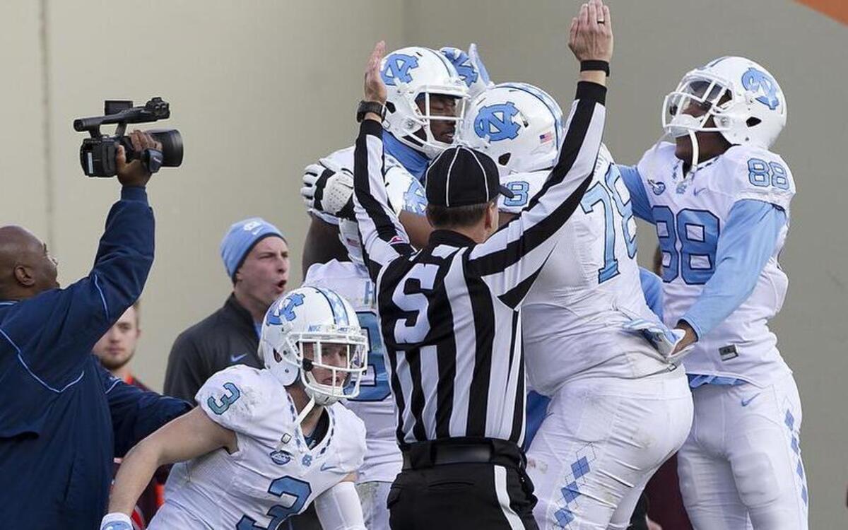 North Carolina’s Quinshad Davis is surrounded by teammates after making the game-winning 5-yard catch from quarterback Marquise Williams in overtime to give the Tar Heels’ a 30-27 victory.