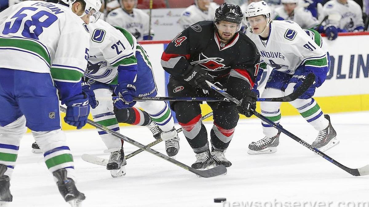 The Carolina Hurricanes' Nathan Gerbe (14), back in the lineup after being out for several weeks with an injury, moves the puck against the Vancouver Canucks' Taylor Fedun (58), Ben Hutton (27), and Jared McCann (91) during the first period of an NHL game played between the Carolina Hurricanes and the Vancouver Canucks at the PNC Arena in Raleigh, N.C. on Jan. 15, 2016.