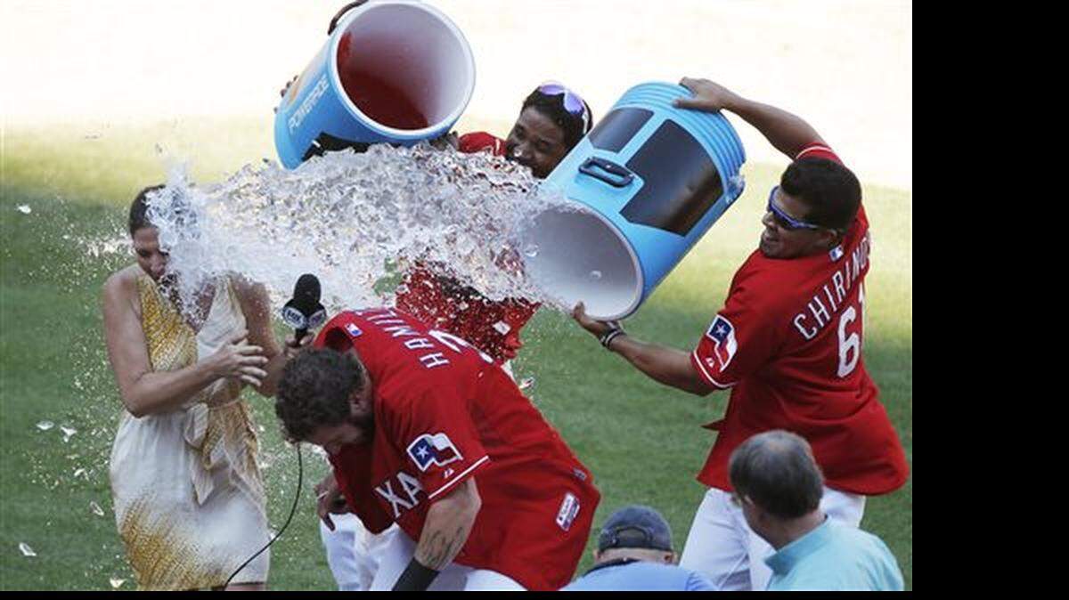 Texas Rangers' Elvis Andrus, background, and Robinson Chirinos, right, douse teammate Josh Hamilton in celebration of his 2 RBI walk-off hit during the ninth inning of a baseball game against the Boston Red Sox, Sunday, May 31, 2015, in Arlington, Texas. Texas won 4-3.