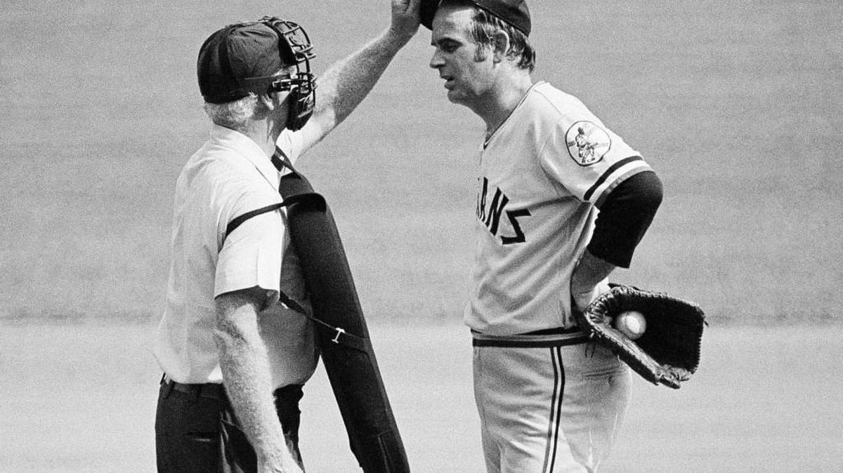 this Sept. 3, 1973, file photo, home plate umpire John Flaherty checks Cleveland Indians pitcher Gaylord Perry's cap for an illegal substance, at the request of Milwaukee Brewers manager Del Crandall, during the first game of a baseball doubleheader in Milwaukee. Blurring the line between legal and illegal, then figuring out how to get away with it, is as old as keeping score. Perry was the spitball king.