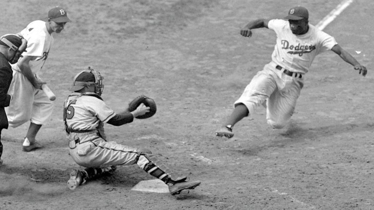Brooklyn Dodgers' Jackie Robinson steals home plate successfully as Boston Braves' catcher Bill Salkeld is thrown off-balance on pitcher Bill Voiselle's throw to the plate during the fifth inning of a Boston-Brooklyn game at Ebbets Field in New York, in this Aug. 22, 1948 file photo. Third baseman Billy Cox, who was at bat, watches Jackie slide. The umpire is Jocko Conlan. The Braves won 4-3.