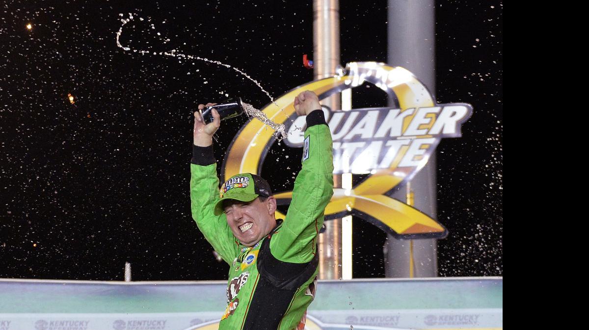 
Kyle Busch sprays his drink in Victory Lane after winning the NASCAR Sprint Cup series auto race at Kentucky Speedway in Sparta, Ky., Saturday, July 11, 2015. 
