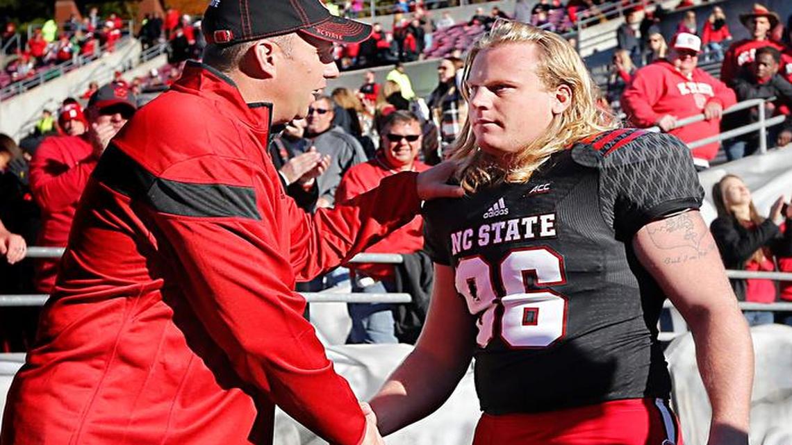 
N.C. State head coach Dave Doeren congratulates Scott Thompson (96) as he is introduced as seniors are recognized before the Wolfpack's game against Wake Forest at Carter-Finley Stadium in Raleigh, N.C., Saturday, Nov. 15, 2014.
