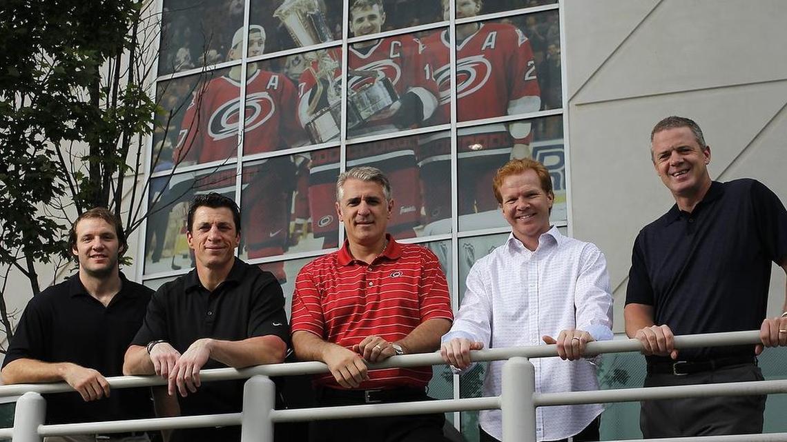 Members of the 2002 NHL Eastern Conference Champion Carolina Hurricanes (L:R) Bates Battaglia, Rod Brind'Amour, Ron Francis, Glen Wesley and Jeff Daniels pose beneath a 2002 photo of team captains Brind'Amour, Francis and Wesley with the Prince of Wales trophy that is on the side of the PNC Arena in Raleigh, NC on May 21,2012. Although the team lost in the Stanley Cup finals to the Detroit Red Wings, from that point on, the popularity of the teams markedly increased in the Triangle and North Carolina.