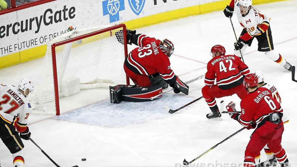 The Flames' Dougie Hamilton (27) gets ready to shoot the puck past the Canes' Scott Darling (33), Joakim Nordstrom (42) and Klas Dahlbeck (6) for his second goal of the game after getting a pass from Matthew Tkachuk (19).