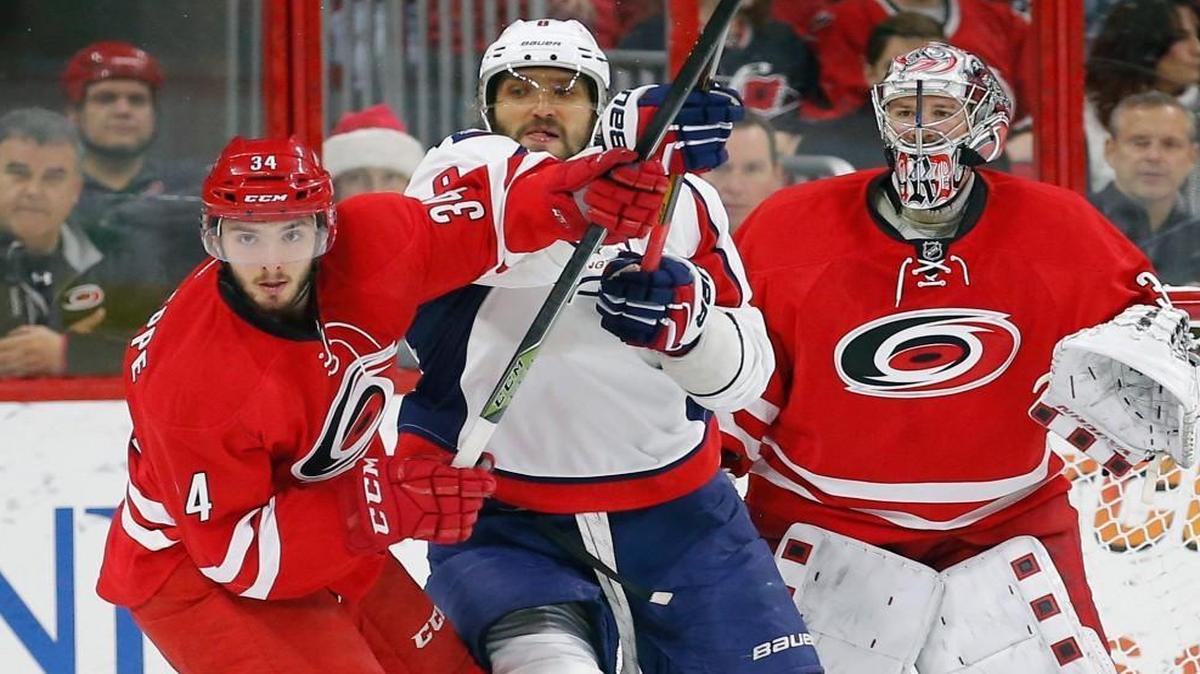 The Carolina Hurricanes' Phil Di Giuseppe (34) and the Washington Capitals' Alex Ovechkin (8) jostle for position in front of the Canes goalie Cam Ward (30) during the first period at PNC Arena in Raleigh.