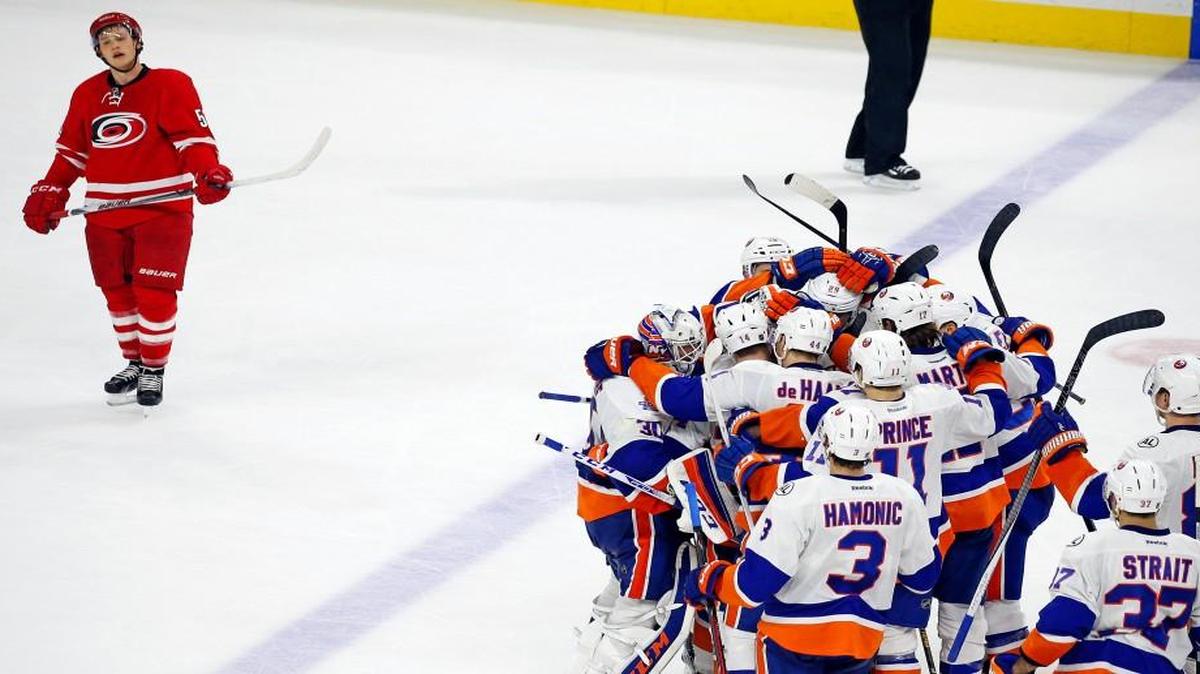 New York Islanders celebrate the winning goal by Cal Clutterbuck as Carolina Hurricanes' Jeff Skinner (53) skates past following overtime of an NHL hockey game, Saturday, March 26, 2016, in Raleigh, N.C. The Islanders won 4-3.