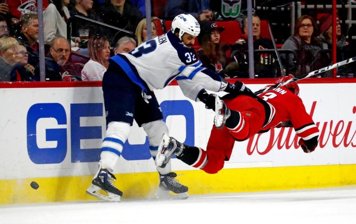The Jets' Dustin Byfuglien (33) puts a hard check on the Canes' Brock McGinn (23) during the first period of an NHL game played between the Carolina Hurricanes and the Winnipeg Jets at PNC Arena.