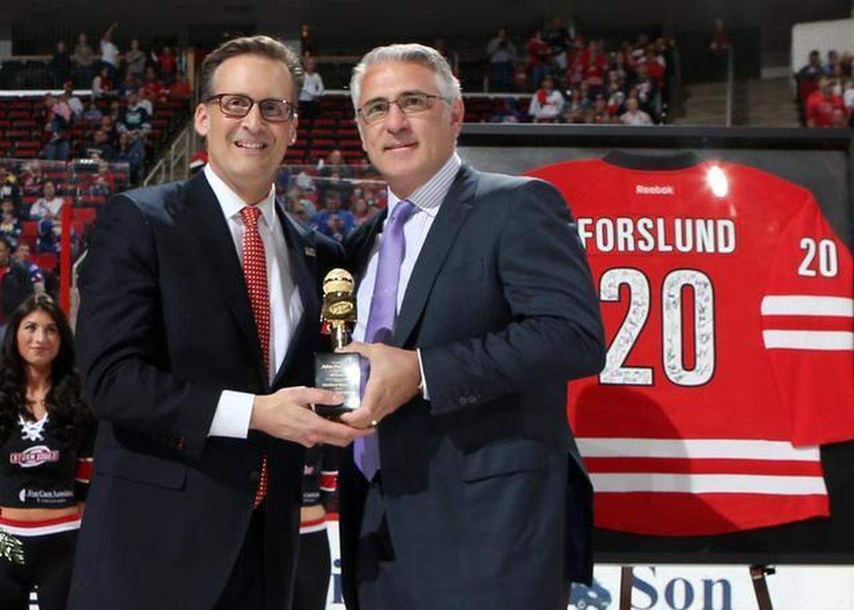 Prior to a 2015 NHL game between the Carolina Hurricanes and New York Rangers, former Hurricanes General Manager Ron Francis presents John Forslund with a golden microphone to recgonize Forslund for serving as the play-by-play voice of the franchise for 20 years.