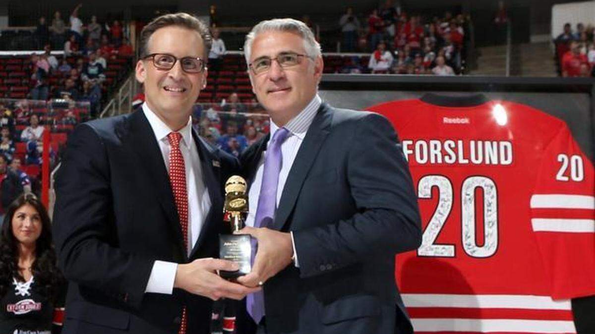 Prior to a 2015 NHL game between the Carolina Hurricanes and New York Rangers, former Hurricanes General Manager Ron Francis presents John Forslund with a golden microphone to recgonize Forslund for serving as the play-by-play voice of the franchise for 20 years.