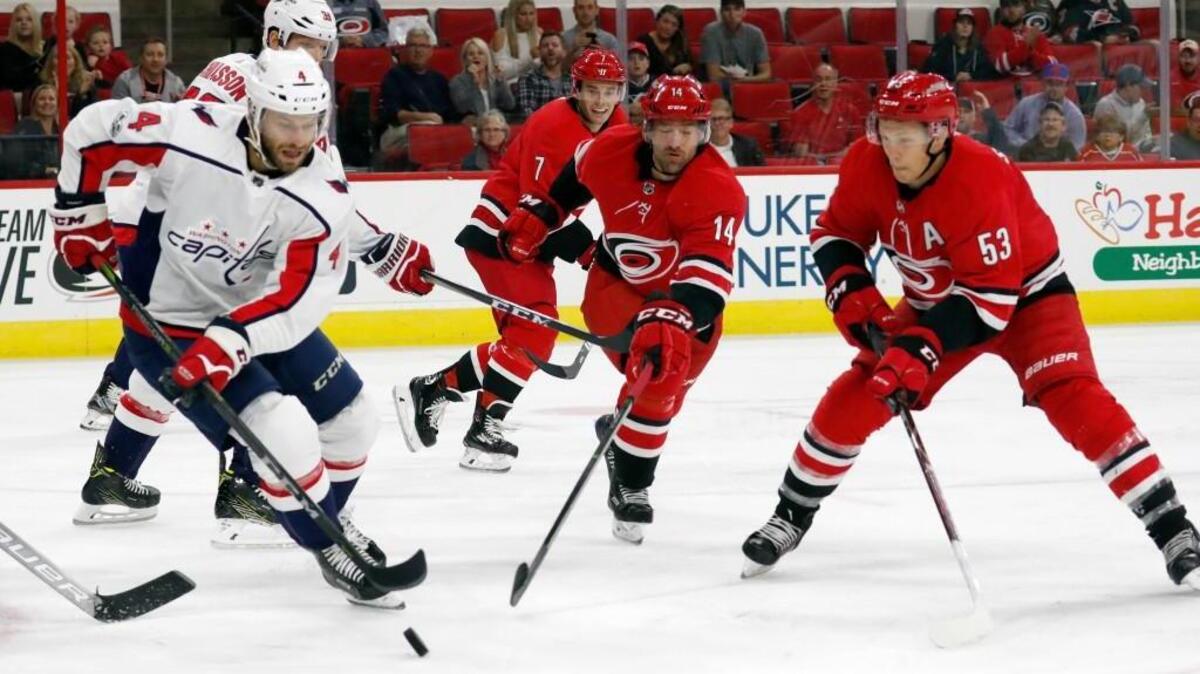 The Canes' Justin Williams (14) and Jeff Skinner (53) fight the Caps' Taylor Chorney (4) for the puck during a preseason NHL game between the Carolina Hurricanes and the Washington Capitals at PNC Arena on Sept. 29, 2017.