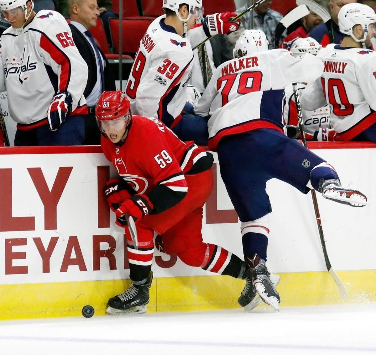The Canes' Janne Kuokkanen (59) avoids a check from the Caps' Nathan Walker (79) during a preseason NHL game played between the Carolina Hurricanes and the Washington Capitals at PNC Arena on Sept. 29, 2017.