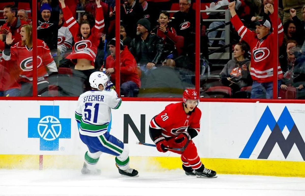 The Canes' Sebastian Aho (20) and the Canes' fans celebrate after he scored against the Canucks' Troy Stecher (51) during the first period of an NHL game played between the Carolina Hurricanes and the Vancouver Canucks at PNC Arena in Raleigh on Friday, Feb. 9, 2018.
