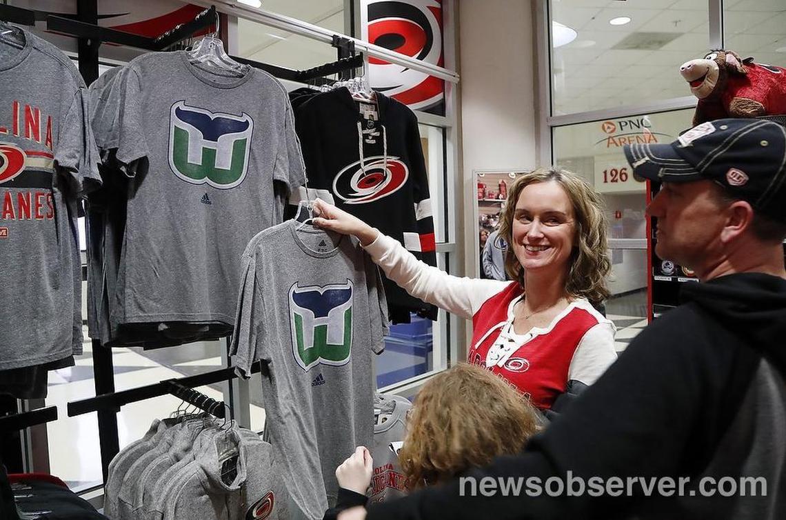 Canes’ fans Jennifer Miller, left, and her husband Lawrence Miller, right, and their daughter Avery Miller, 9, bottom, check out the Hartford Whalers tee shirts for sale at The Eye. They bought the first Whalers items.