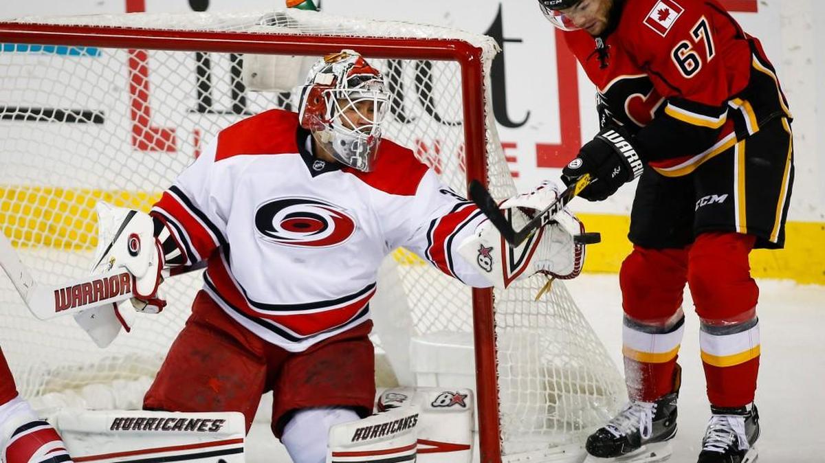 Carolina Hurricanes goalie Eddie Lack, left, from Sweden, grabs for the puck as Calgary Flames' Michael Frolik, from Czech Republic, swats at it during the second period of an NHL hockey game, Thursday, Oct. 20, 2016 in Calgary, Alberta.