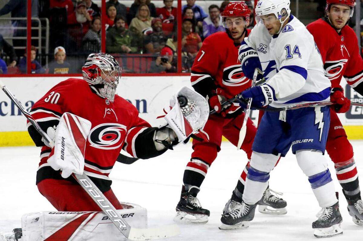The Canes' Cam Ward (30) snags the puck in front of Derek Ryan (7) and the Lightning's Chris Kunitz (14) during the second period of an NHL game played between the Carolina Hurricanes and the Tampa Bay Lightning at PNC Arena in Raleigh, N.C. on April 7, 2018. The Canes beat the Lightning 3-2 in overtime in the Canes' final game of the season.