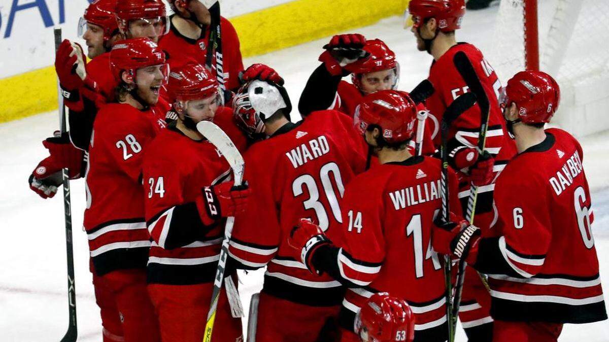 The Canes' Elias Lindholm (28) celebrates his winning goal with goaltender Cam Ward (30) and other teammates at the end of the the Hurricanes' season-ending 3-2 overtime win over the Tampa Bay Lightning on Saturday, April 7, 2018.
