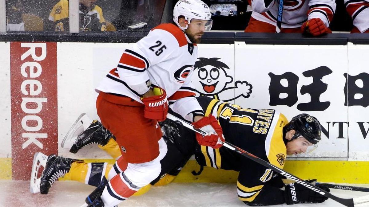Boston right wing Jimmy Hayes, right, goes down along the boards as he chases the puck along with Carolina left wing Viktor Stalberg during their game Thursday night in Boston.