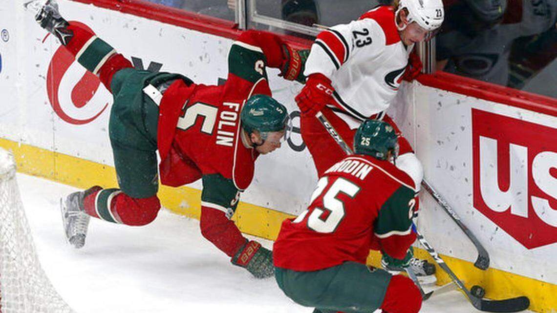 The Minnesota Wild's Christian Folin, left, of Sweden, gets tripped up chasing the puck with Carolina Hurricanes' Brock McGinn in the first period of an NHL hockey game Tuesday, April 4, 2017, in St. Paul, Minn.