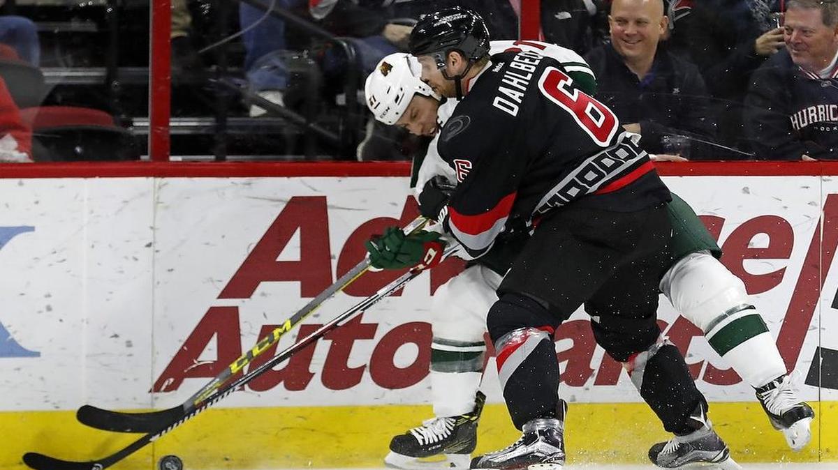 The Canes' Klas Dahlbeck (6) hit the Minnesota Wild's Ryan White (21) as they fight for the puck during the first period of an NHL game played between the Carolina Hurricanes and the Minnesota Wild at PNC Arena in Raleigh, N.C. on March 16, 2017.