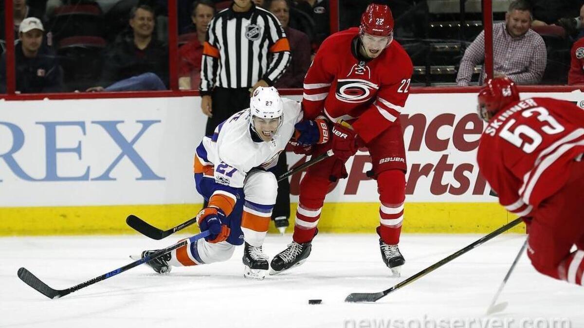 The Carolina Hurricanes' Brett Pesce (22) and Jeff Skinner (53) battle the New York Islanders' Anders Lee (27) for the puck during the second period.