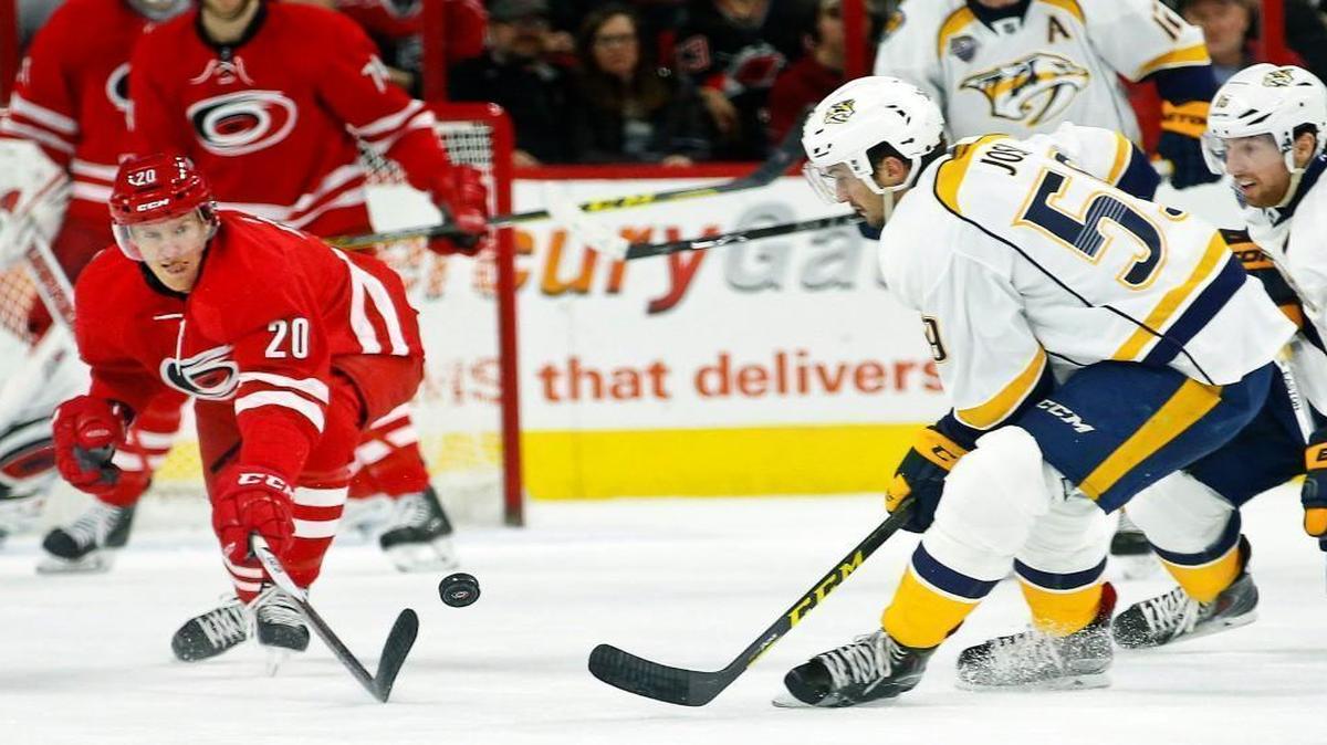 The Carolina Hurricanes' Riley Nash (20) pokes the puck away from the Nashville Predators' Roman Josi (59) and James Neal (18) during the second period at PNC Arena in Raleigh.
