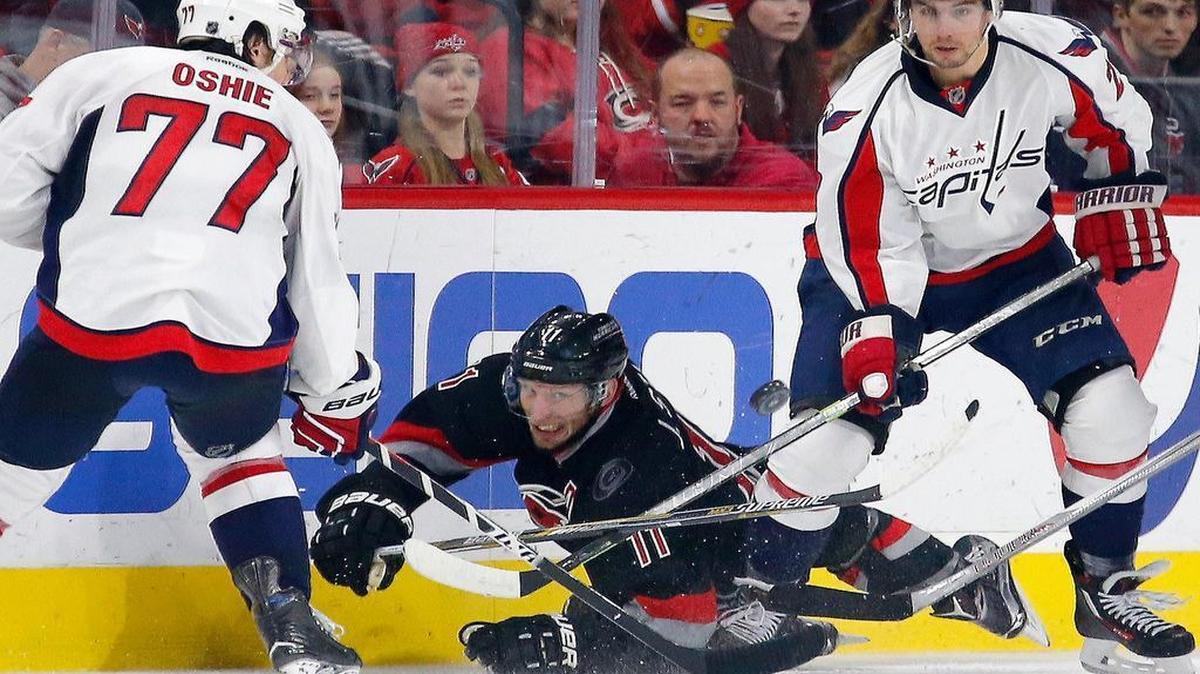The Carolina Hurricanes' Jordan Staal (11) dives for the puck as he battles the Washington Capitals' T.J. Oshie (77) and Matt Niskanen (2) during the second period of an NHL game played between the Carolina Hurricanes and the Washington Capitals at PNC Arena in Raleigh, N.C. on Dec. 31, 2015.