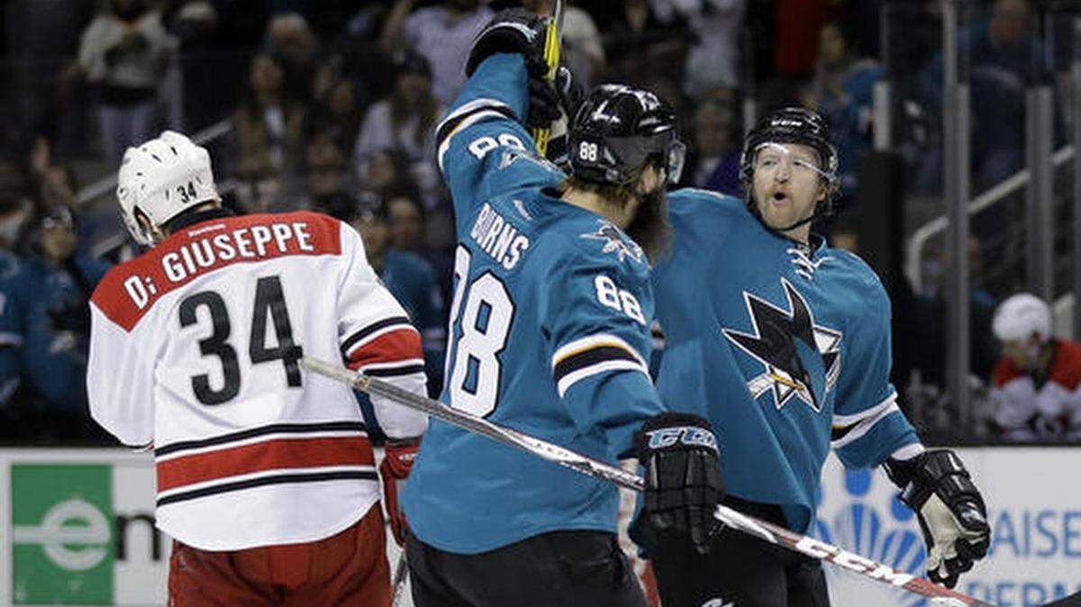 San Jose Sharks' Paul Martin, right, celebrates his goal with teammate Brent Burns (88) next to Carolina Hurricanes' Phillip Di Giuseppe (34) during the first period of an NHL hockey game Saturday, Dec. 10, 2016, in San Jose, Calif.