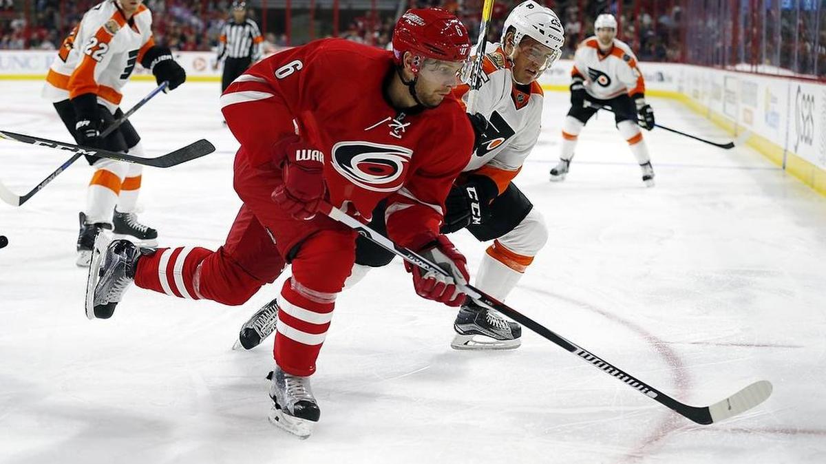 The Canes' Klas Dahlbeck (6) and the Philadelphia Flyers' Nick Cousins (25) go for the puck.