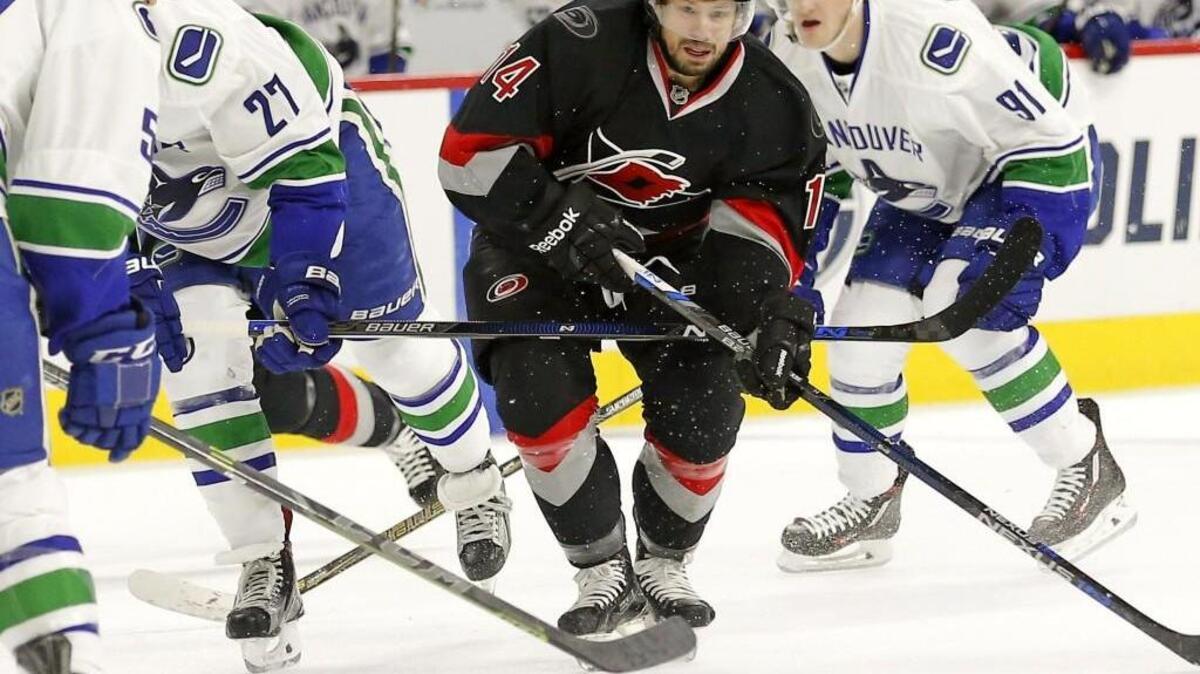 The Carolina Hurricanes' Nathan Gerbe (14), back in the lineup after being out for several weeks with an injury, moves the puck against the Vancouver Canucks' Taylor Fedun (58), Ben Hutton (27), and Jared McCann (91) during the first period of an NHL game played between the Carolina Hurricanes and the Vancouver Canucks at the PNC Arena on Jan. 15.