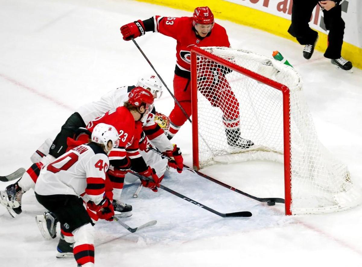 The Canes' Jeff Skinner (53) puts the puck past the Devils' Blake Coleman (40), Andy Greene (6) and Keith Kinkaid (1) for a goal during the final moments of the third period as Brock McGinn (23) also charges in. It was Skinner's 200th career goal. The Devils beat the Canes 3-2 in overtime.