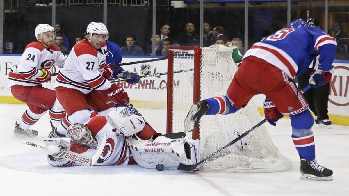 Carolina Hurricanes' Cam Ward (30) stops a shot on the goal by New York Rangers' Kevin Hayes, right, as teammates Justin Faulk (27) and Brad Malone (24) watch during the second period.