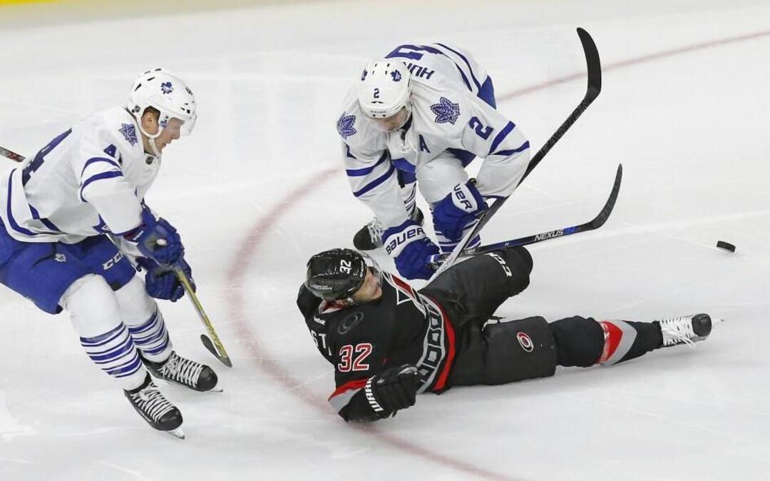 The Canes’ Kris Versteeg (32) hits the ice as he battles the Leafs Morgan Rielly (44) and Matt Hunwick (2) during the third period at PNC Arena in Raleigh.