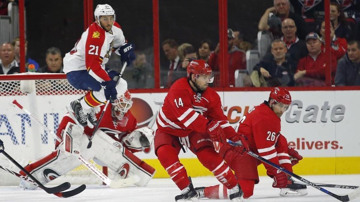 
The Florida Panthers' Vincent Trocheck (21) jumps to get out of the way of a teammate's shot as the Carolina Hurricanes' Eddie Lack (31), Nathan Gerbe (14) and John-Michael Liles (26) defend during the first period of an NHL game played between the Carolina Hurricanes and the Florida Panthers at PNC Arena in Raleigh, N.C. on Oct. 13, 2015.
