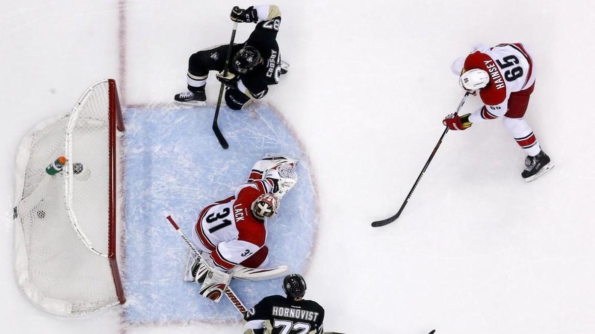 Pittsburgh Penguins' Sidney Crosby, top, gets a shot past Carolina Hurricanes goalie Eddie Lack (31) during the second period in Pittsburgh,.