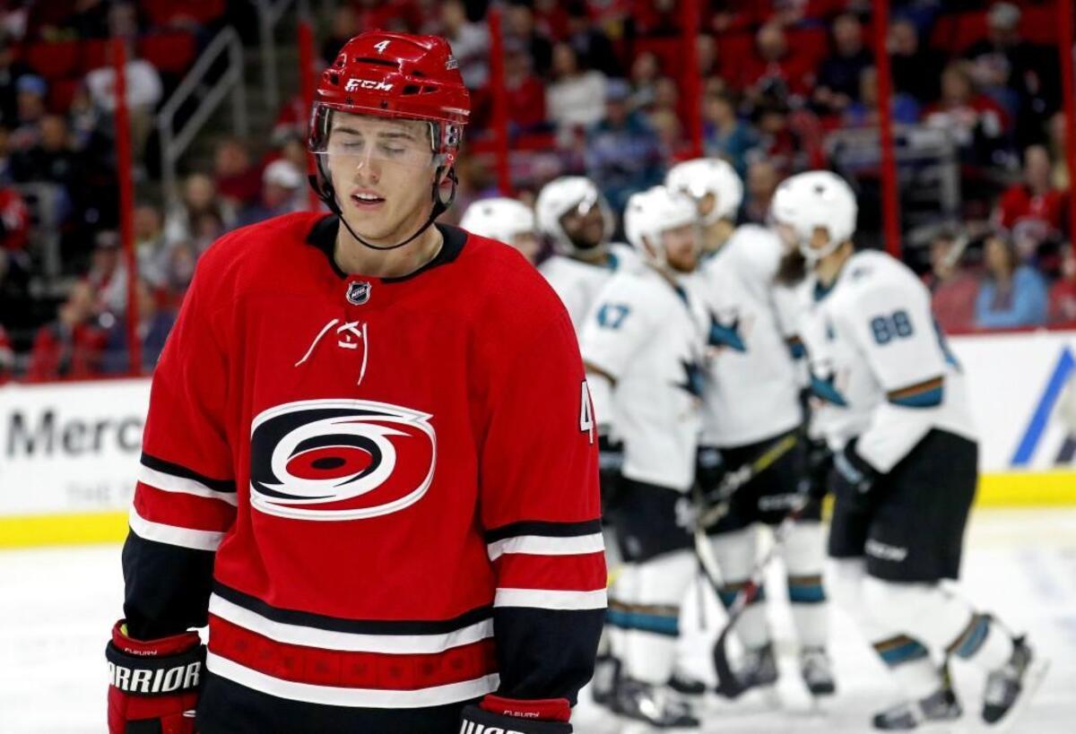 The Canes' Haydn Fleury (4) skates away as the Sharks' Brent Burns (88) celebrates his goal with teammates during the second period of an NHL game played between the Carolina Hurricanes and the San Jose Sharks at PNC Arena on Feb. 4, 2018.