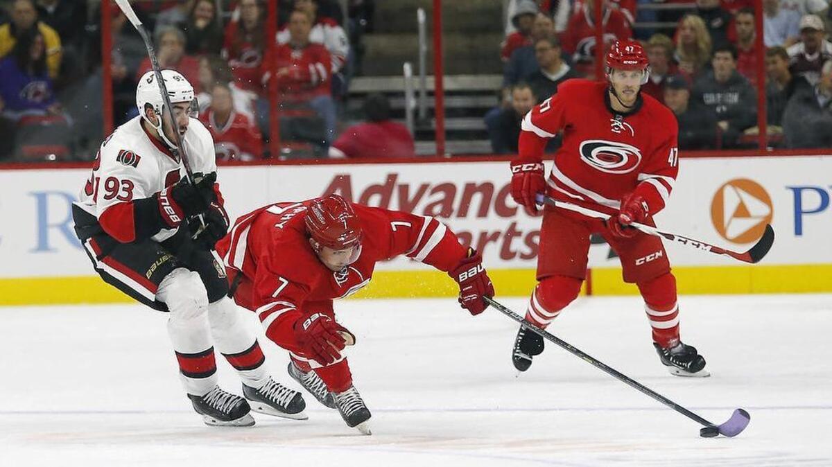The Canes Ryan Murphy (7) reaches for the puck in front of the Ottawa Senators' Mika Zibanejad (93) during the first period. The Canes Michal Jordan (47) looks on.