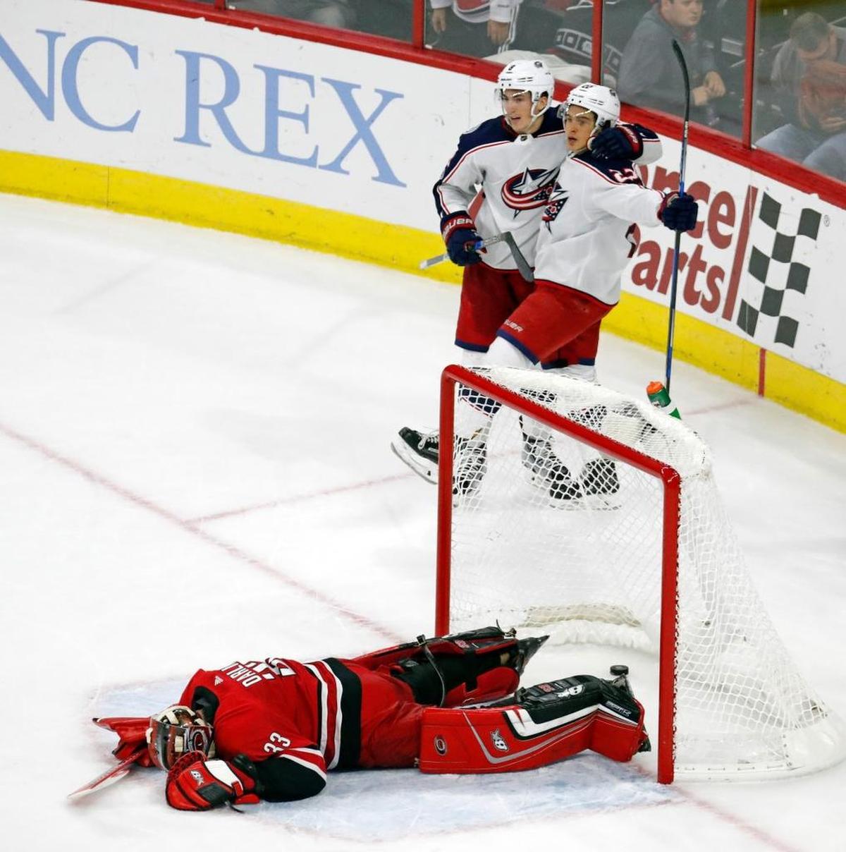 The Blue Jackets' Sonny Milano (22) celebrates with Zach Werenski (8) after he put the puck past the Canes' Scott Darling (33) for the winning shot in overtime.