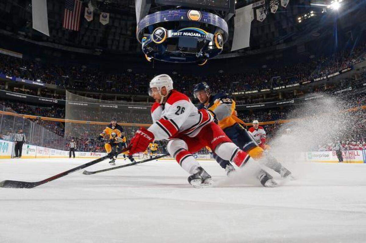 
John-Michael Liles of the Carolina Hurricanes controls the puck against Johan Larsson of the Buffalo Sabres on Monday at the First Niagara Center in Buffalo, N.Y. 
