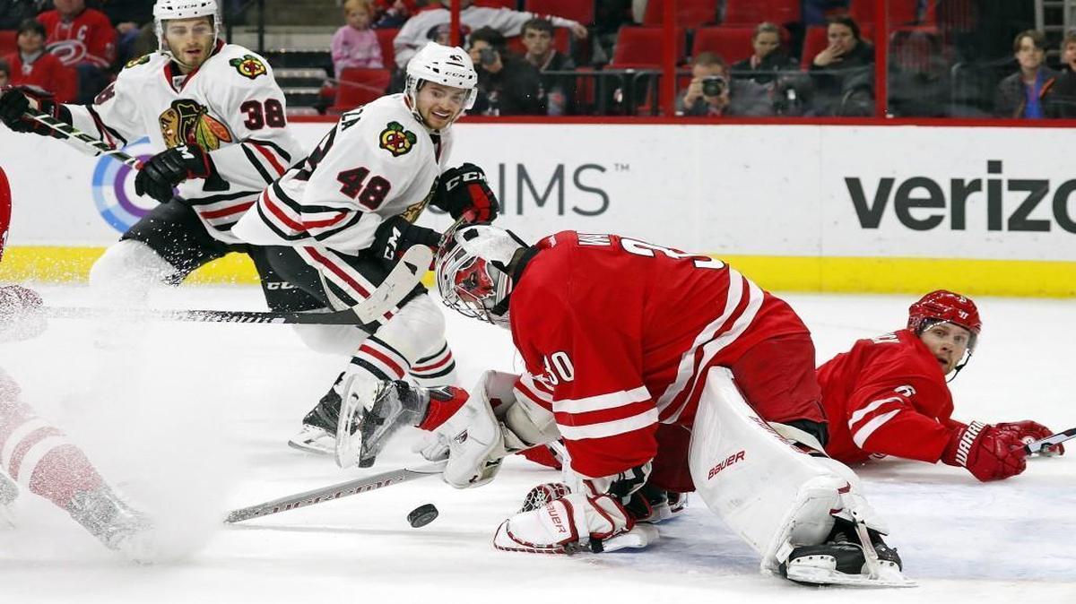 Carolina Hurricanes goalie Cam Ward freezes the puck after it is shot by Chicago Blackhawks' Vinnie Hinostroza (48) with Hawks Ryan Hartman (38) looking on during the first period.
