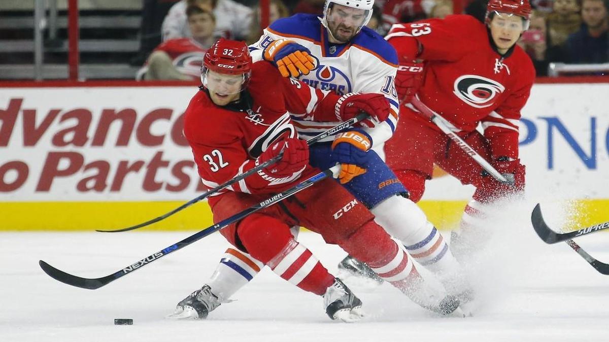 The Canes Kris Versteeg (32) battles the Edmonton Oilers' Teddy Purcell (16) for the puck.